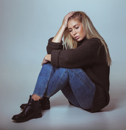 Pensive Woman In Sweater Sitting On Floor